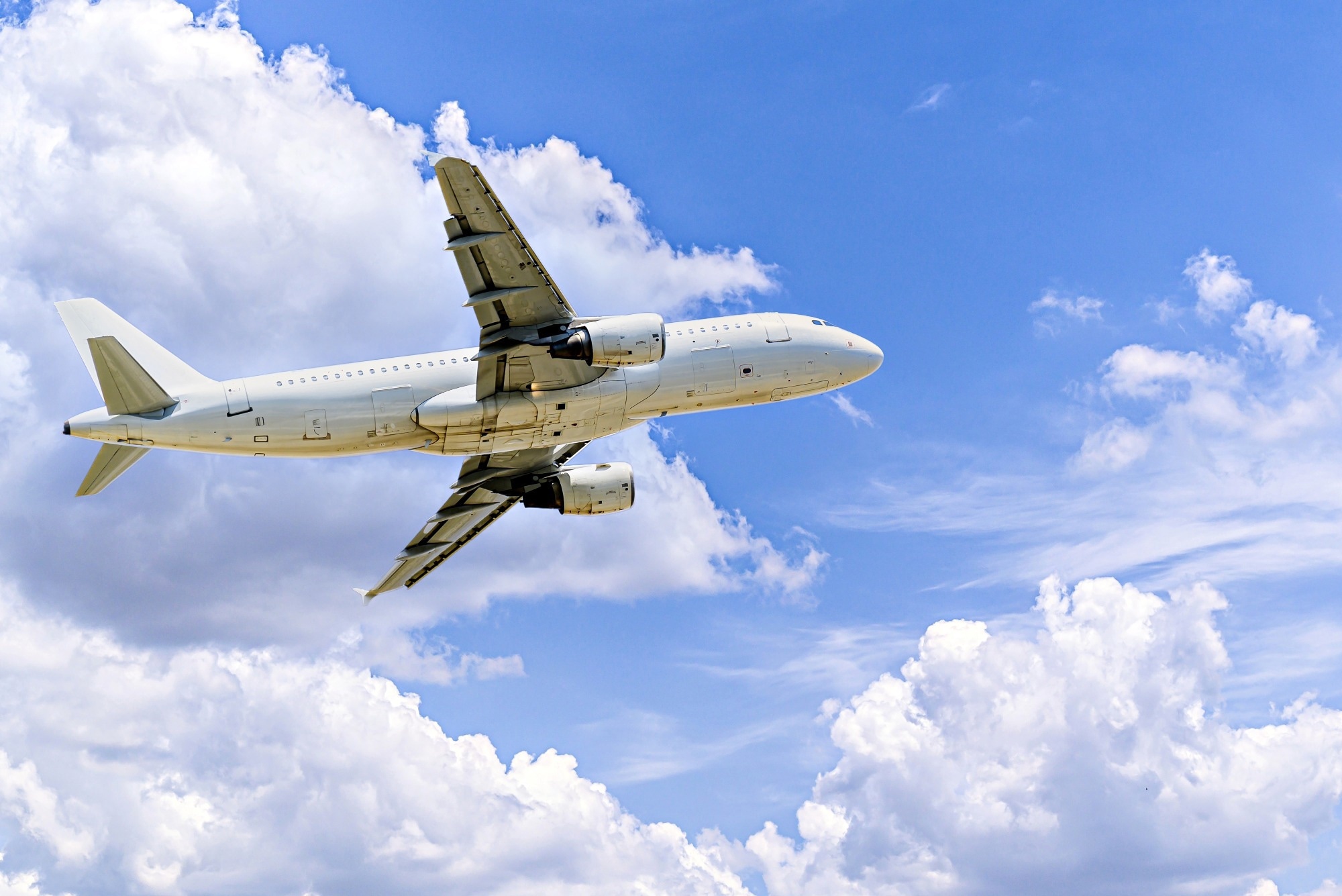 Passenger plane under a blue sky with white clouds.