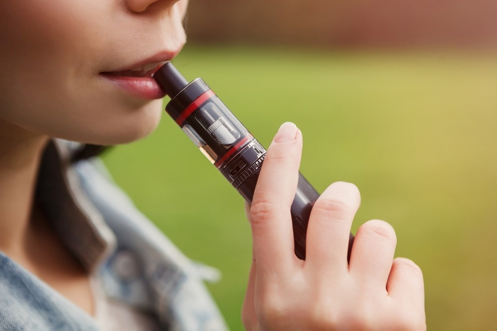 Young girl smoking vape cigarettte. Vaper smokes e-cig in close up