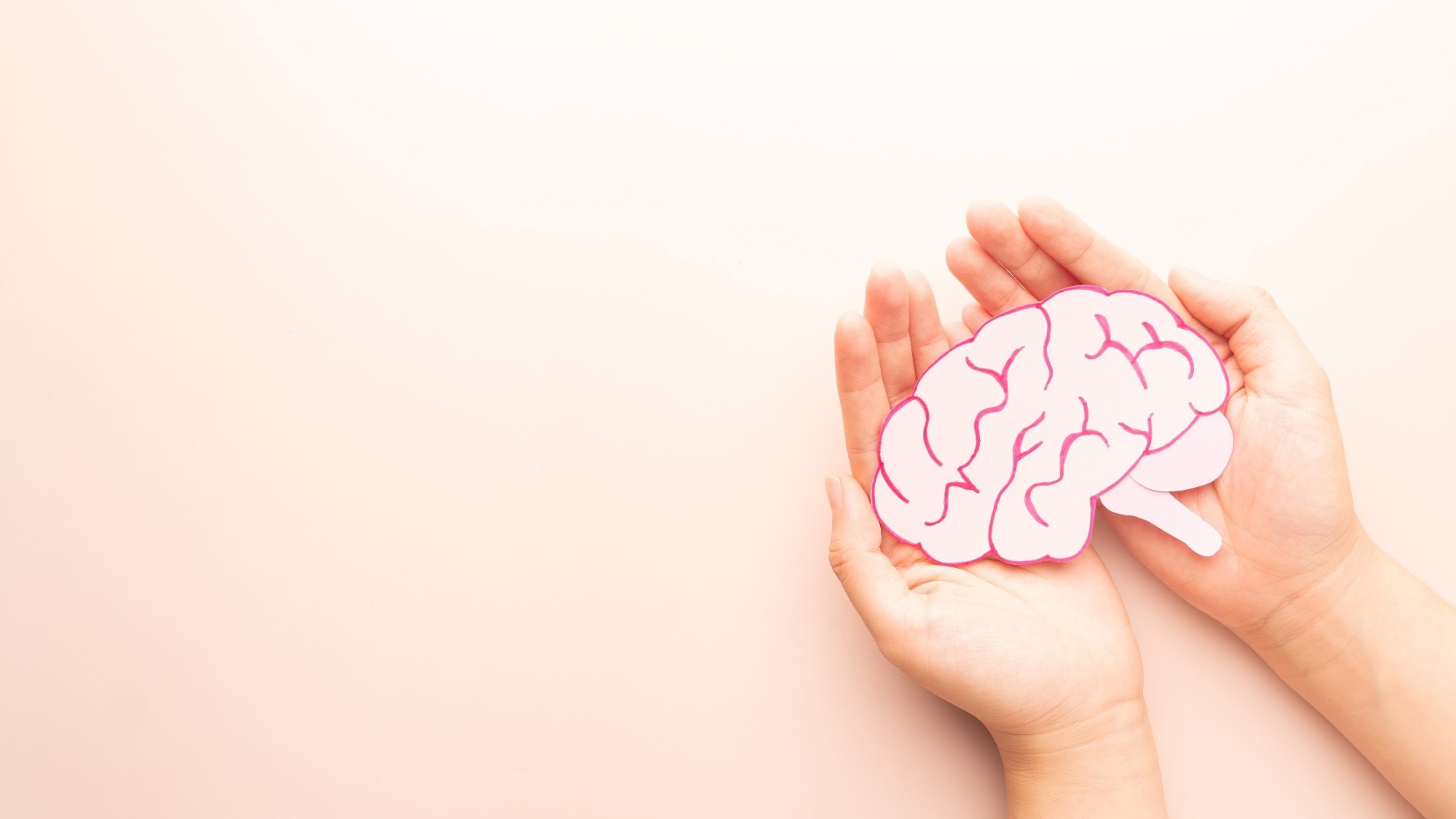 Woman hands holding human brain shape made from paper on beige background. Awareness of Alzheimer, Parkinson