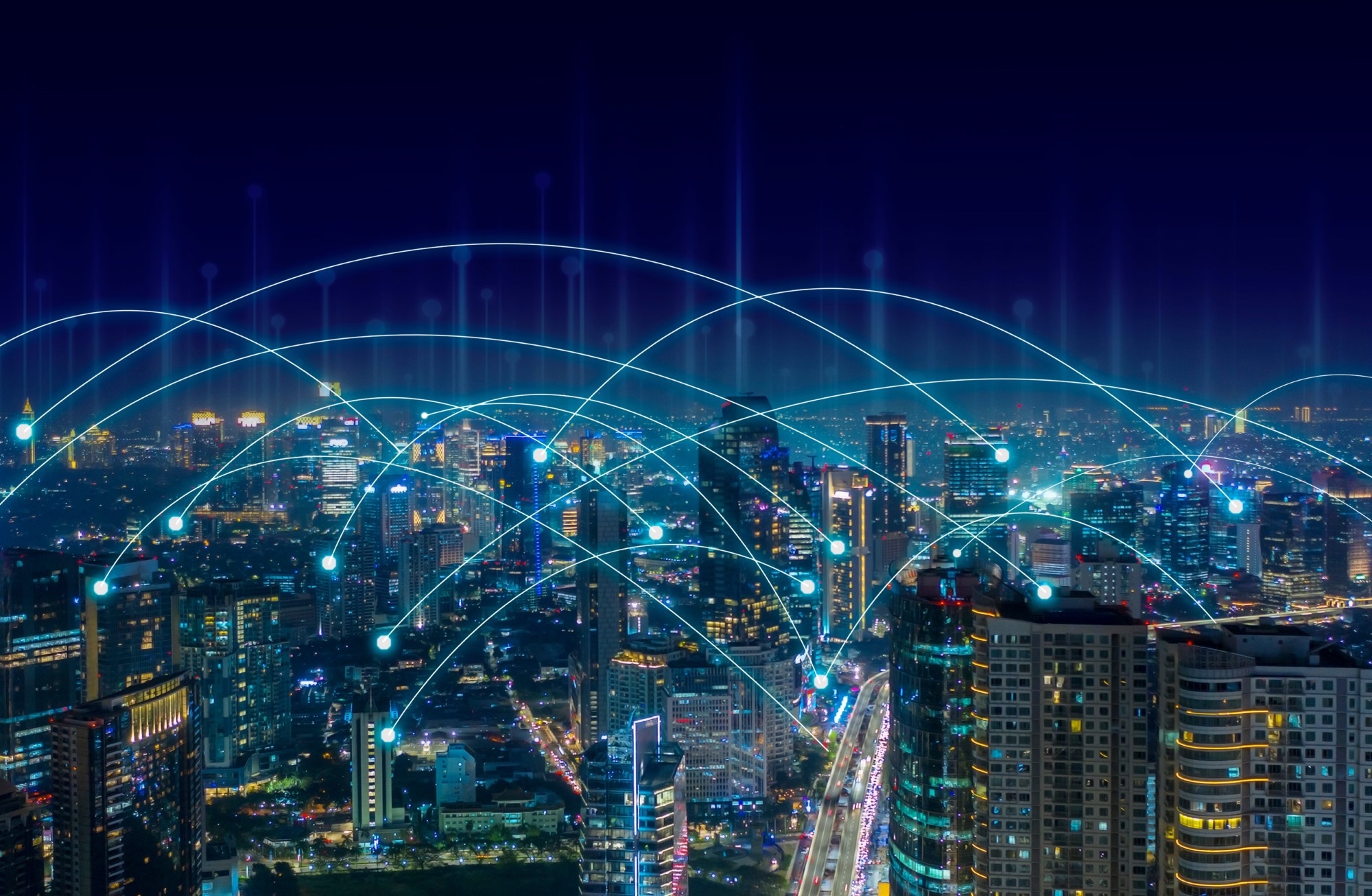 Smart city concept design with lit up buildings and light travelling from city block to block.