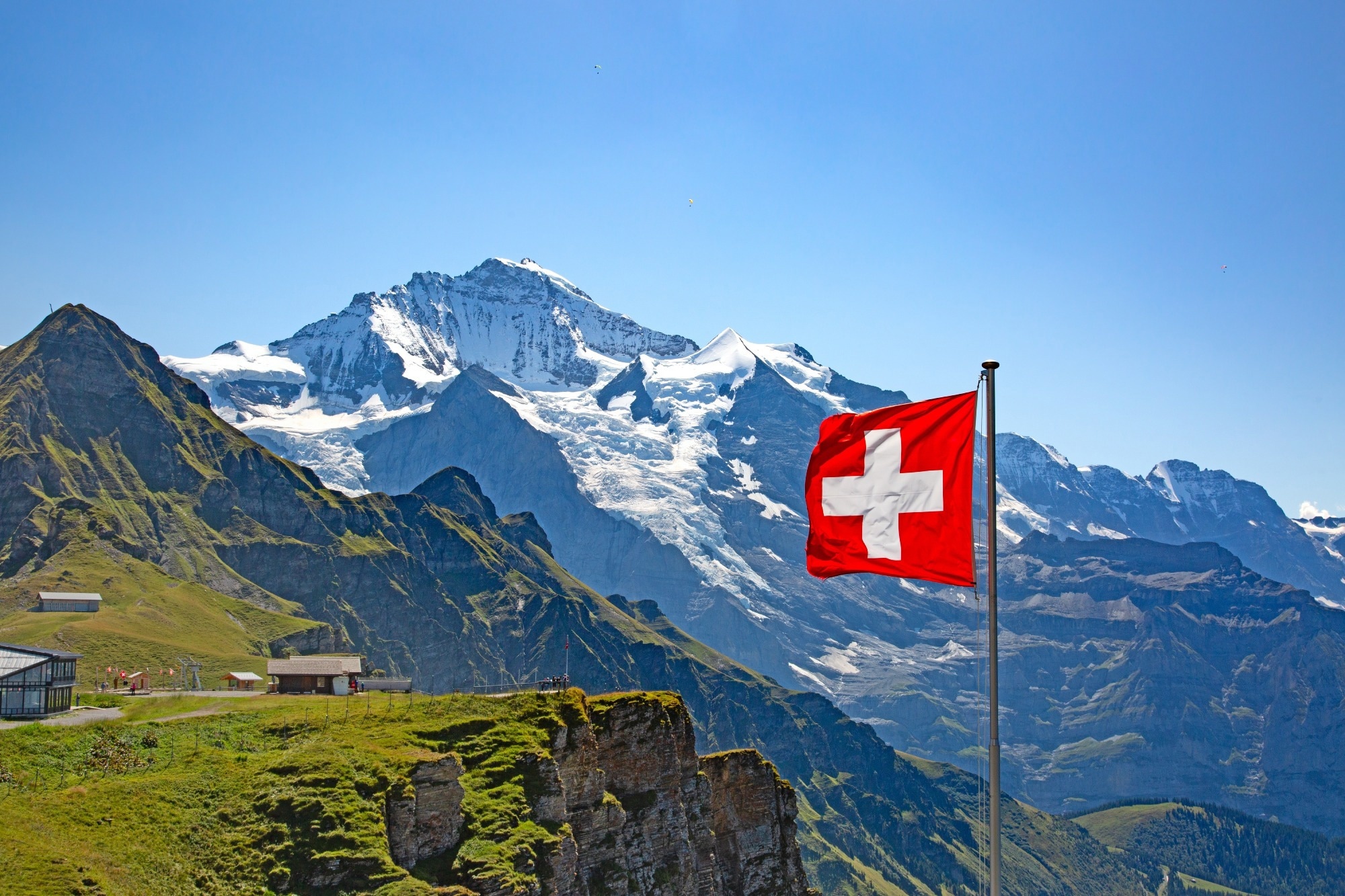 A mountain landscape in the Jungfrau region, with a swizz flag in the front right.