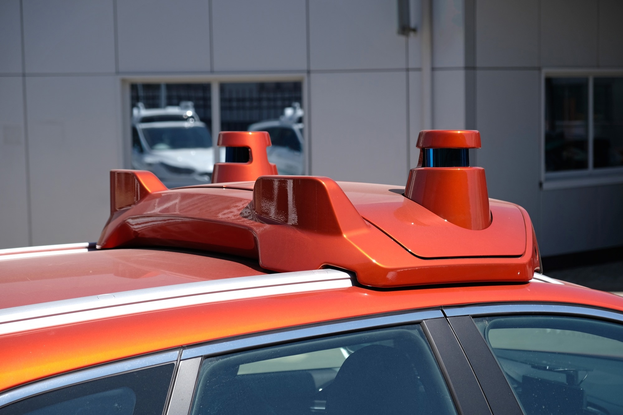 Sensing system in an autonomous driving car. The car is red with two sensor scanning ports located on the roof.