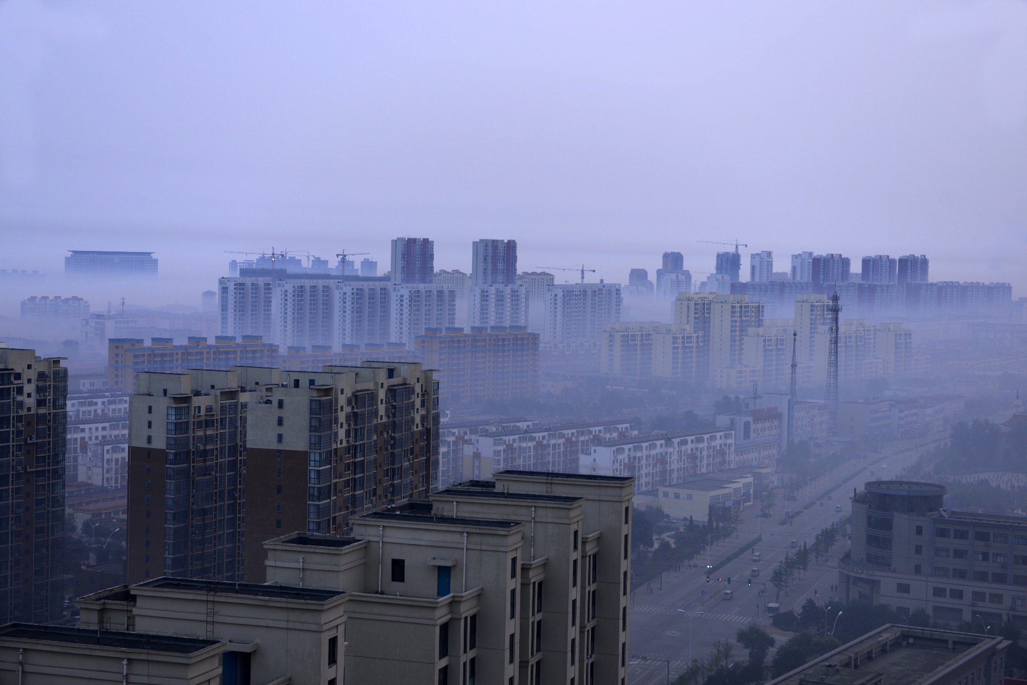 Smoke hangs over the rooftops of a cityscape.