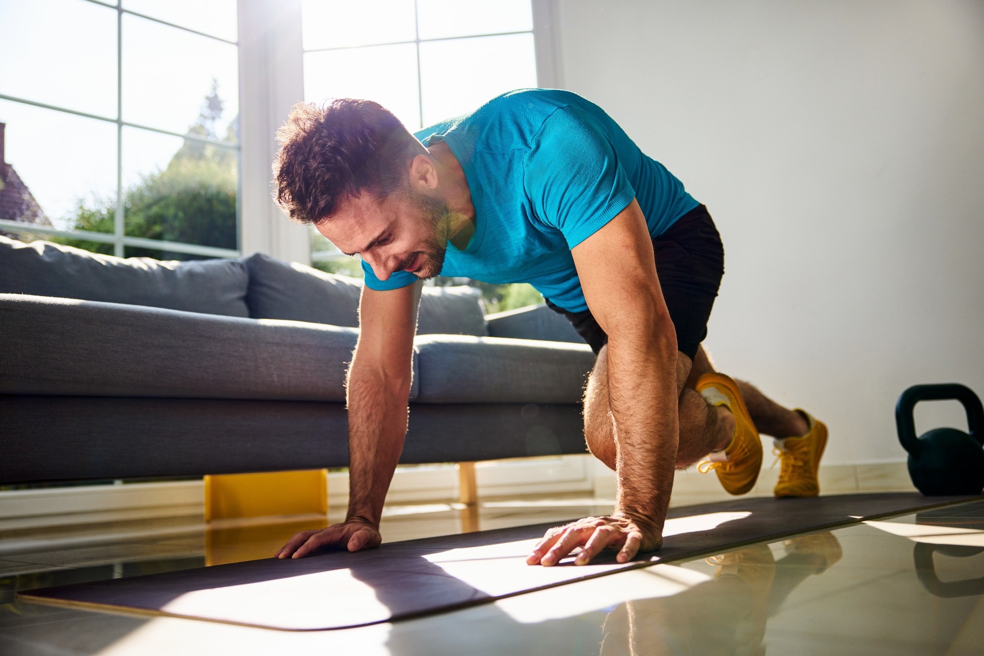 A man doing exercise on a yoga mat in his living room.