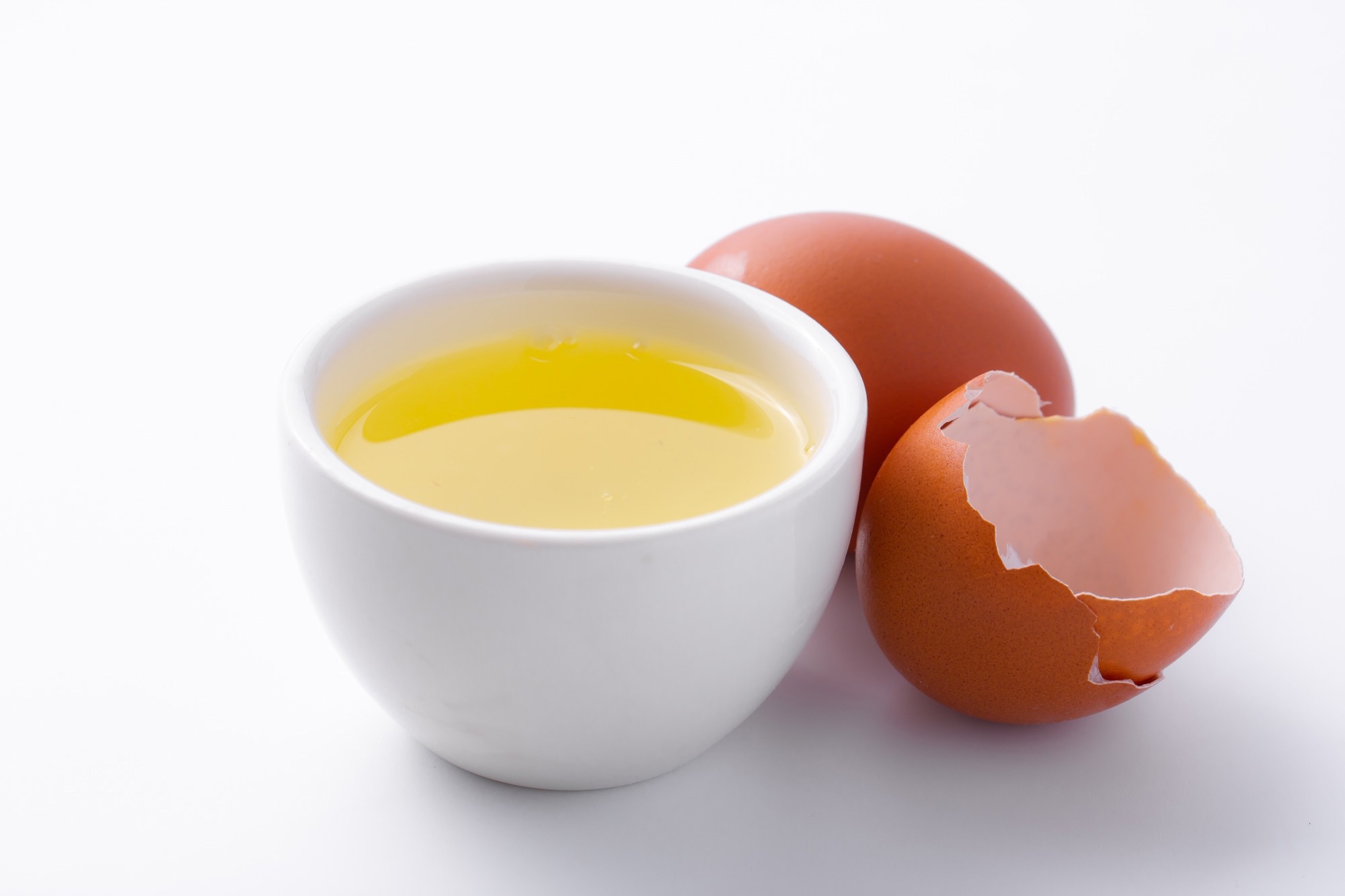 Egg whites in glass cup on white background.