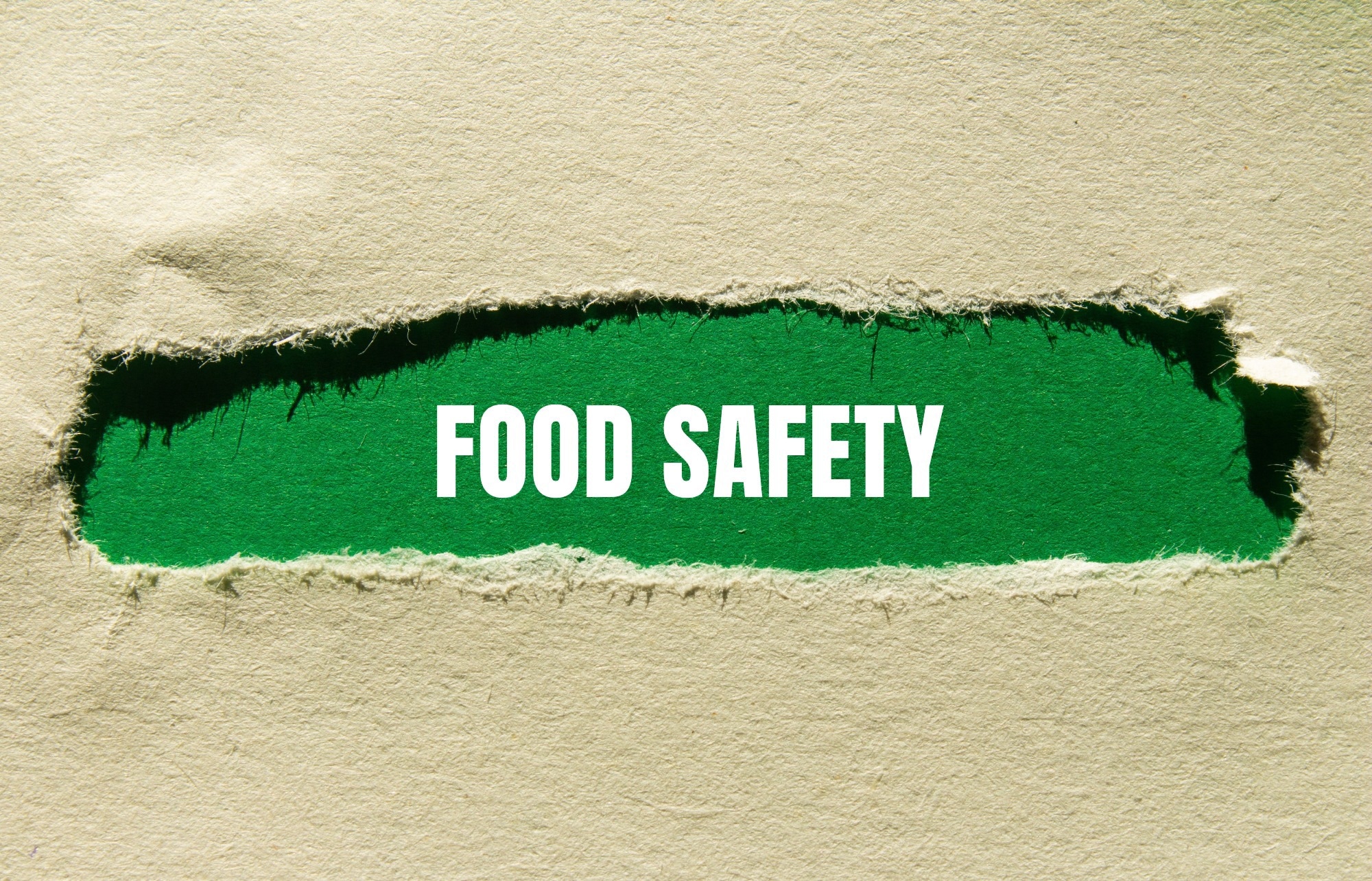Food safety message written on ripped torn paper with green background.