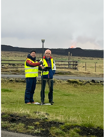 Jiaxuan Li and a colleague in Iceland with a lava eruption in the distance.