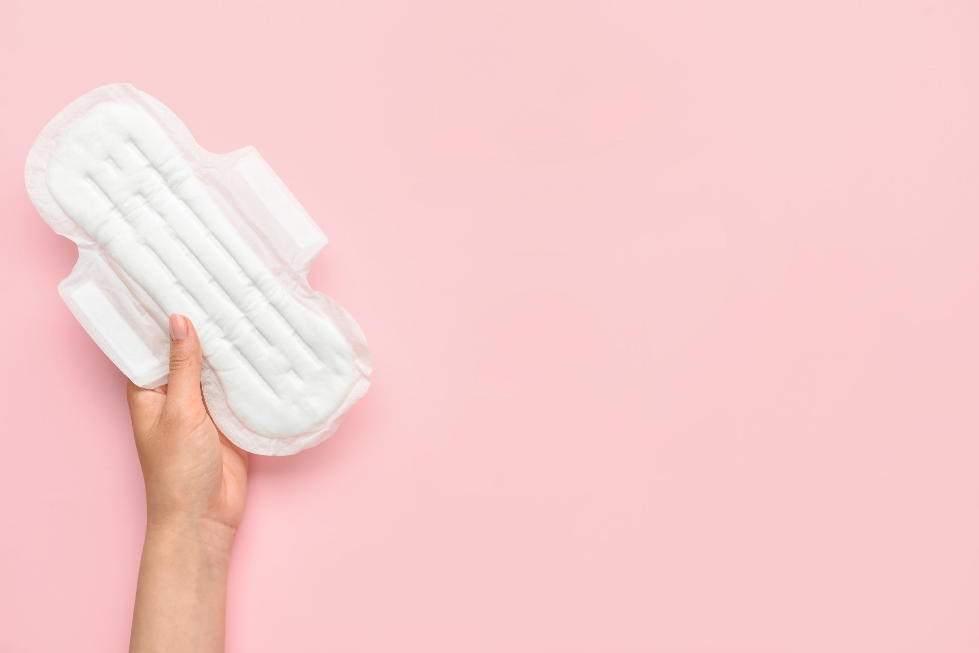 Female hand with menstrual pad on pink background