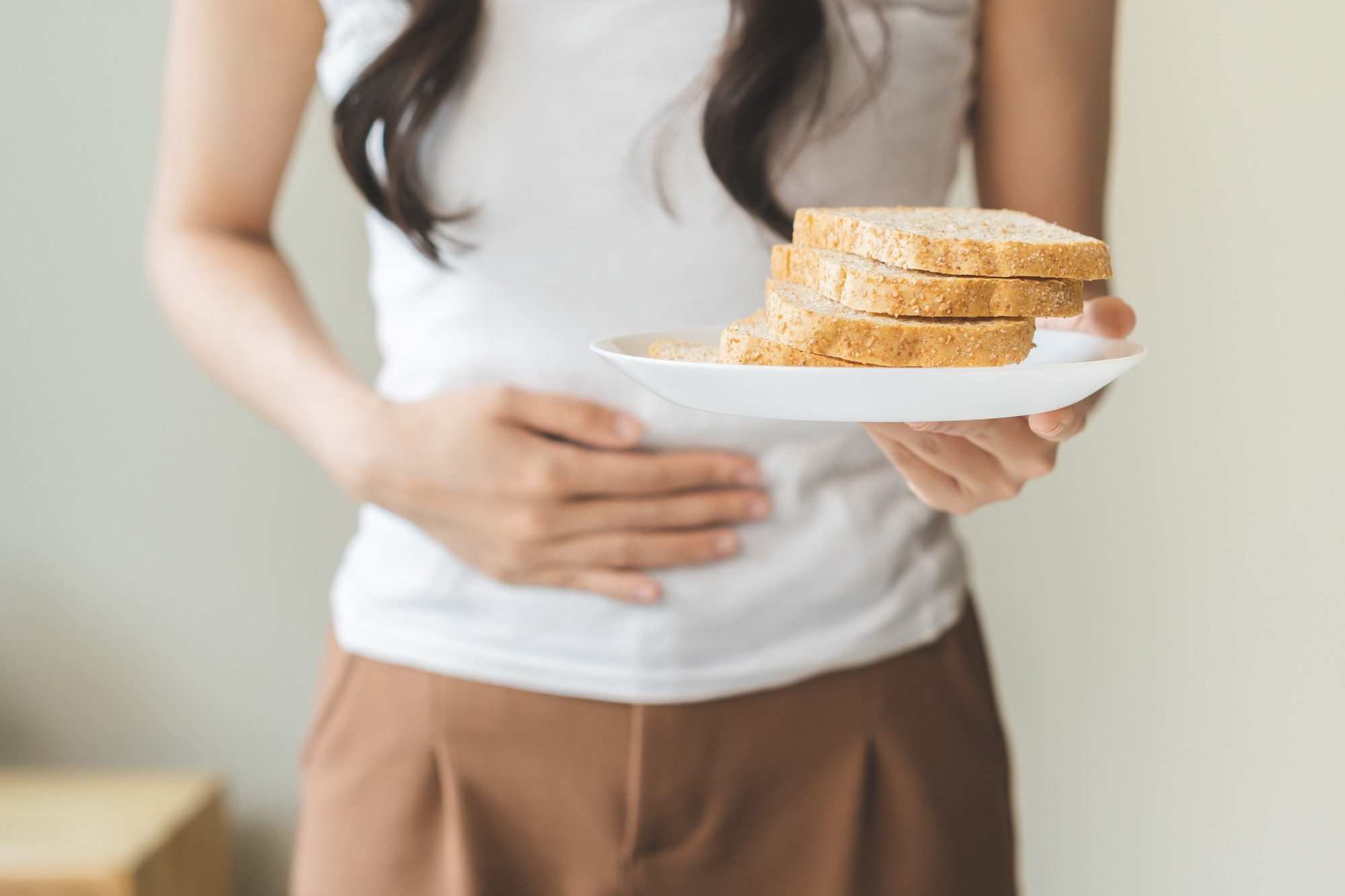 Gluten allergy. Young woman refusing to eat white bread slice on plate. Gluten free diet concept.