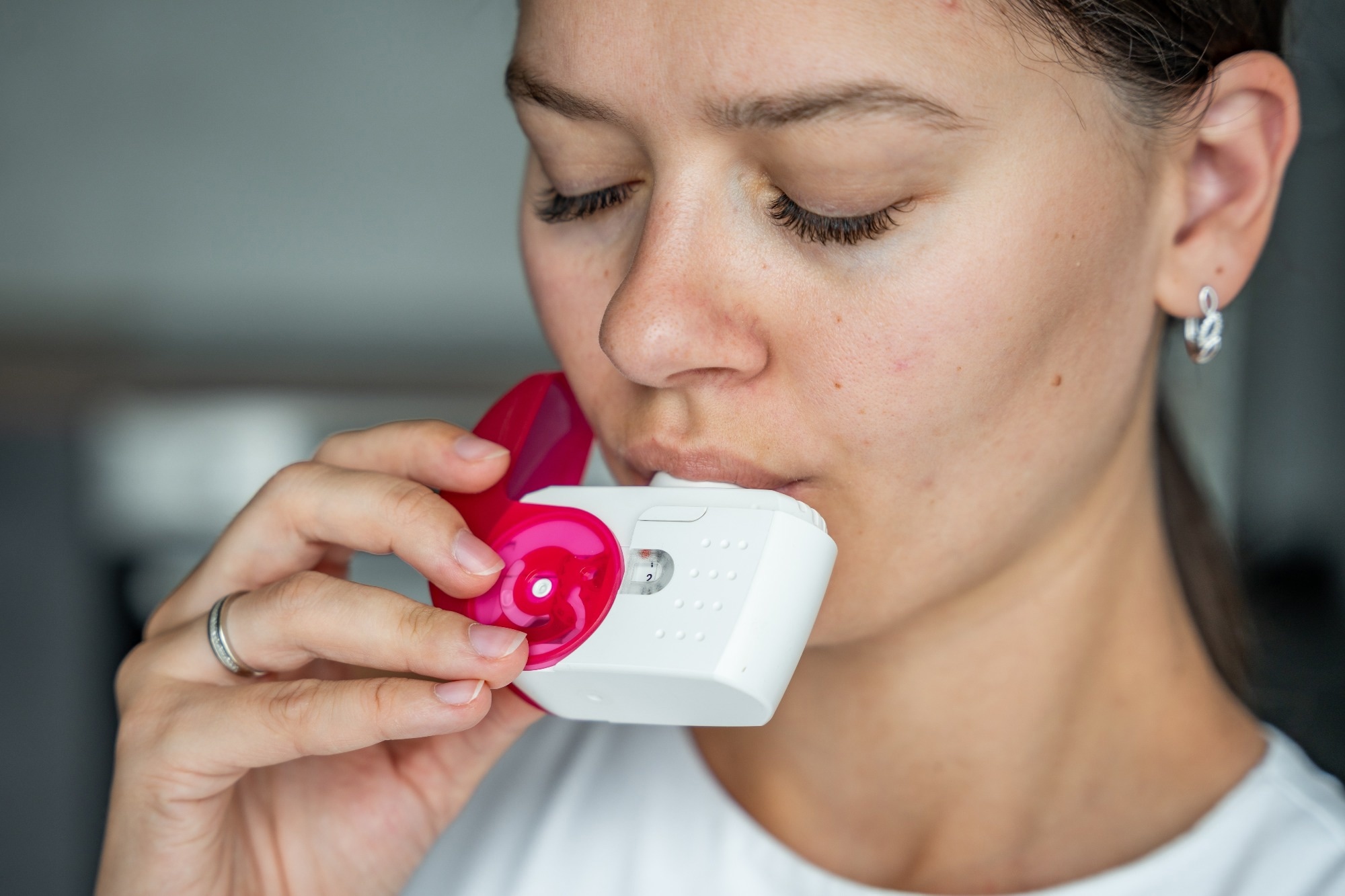 Close up view of woman using medicine dry powder inhaler for treatment asthma or COPD diseases. Pharmaceutical product is used to treat lung inflammation and prevent asthma attack. High quality photo