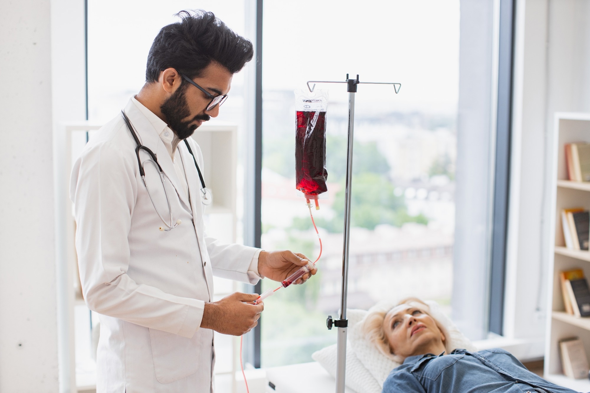 A doctor monitoring an older female patients bloods.