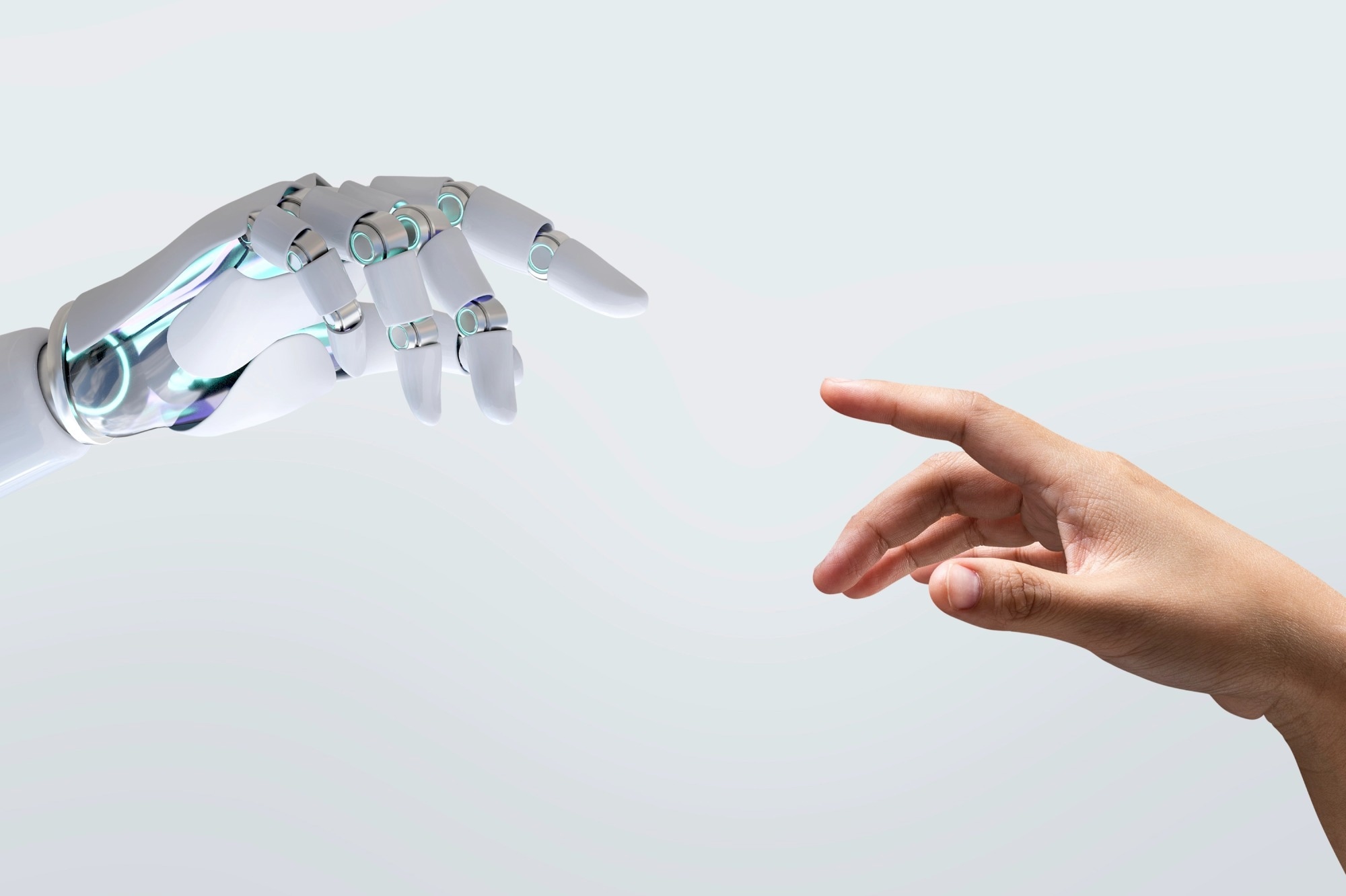 A robotic hand and a human hand point towards each other, almost touching. White background.
