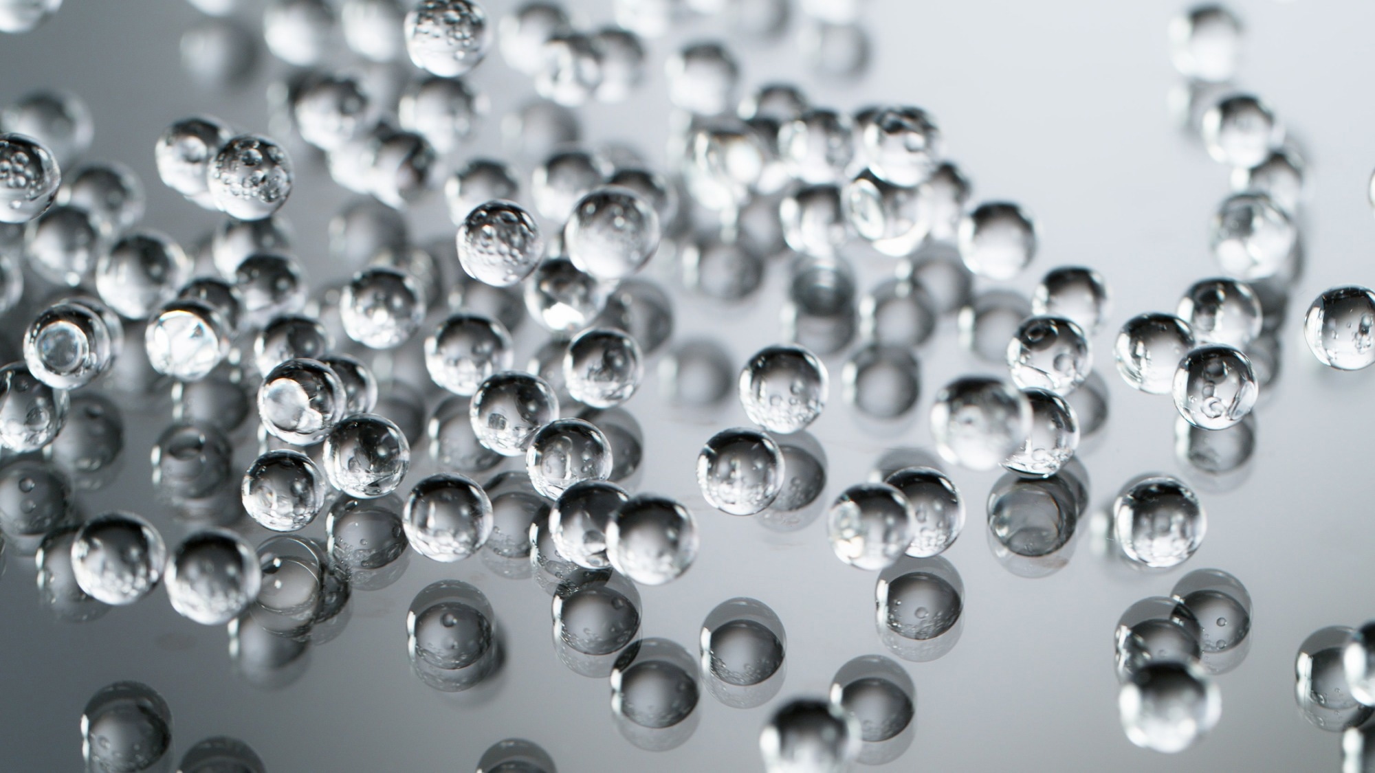 Hydrogel droplets against a grey background, slightly blurred.