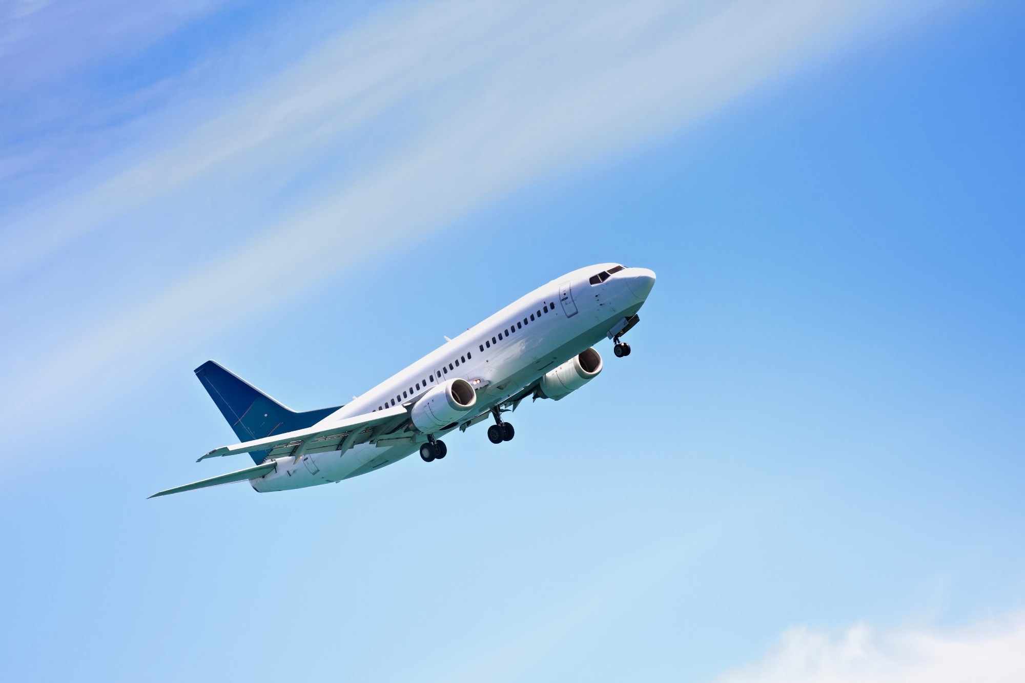 A plane taking flight against a blue, cloudy sky.