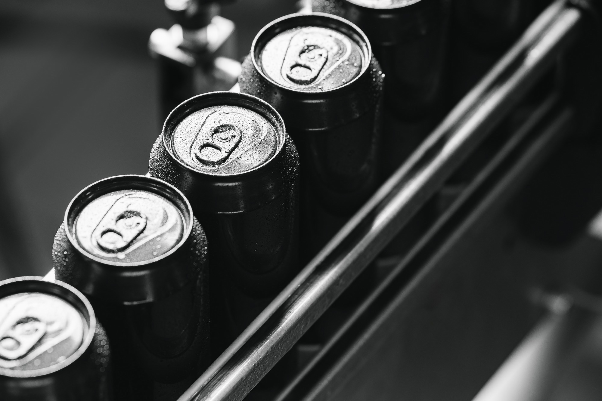 Beverage cans in row at modern assembly line, top view.