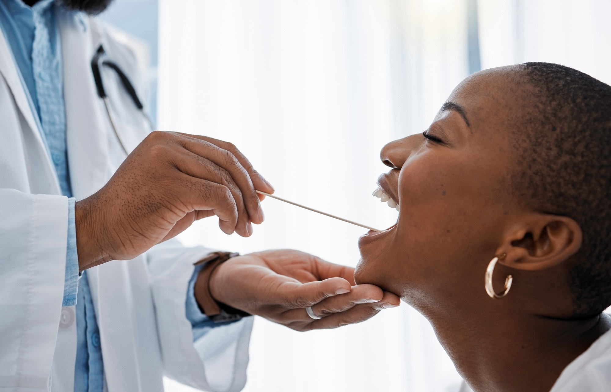 Doctor using a medical instrument to check a female patient