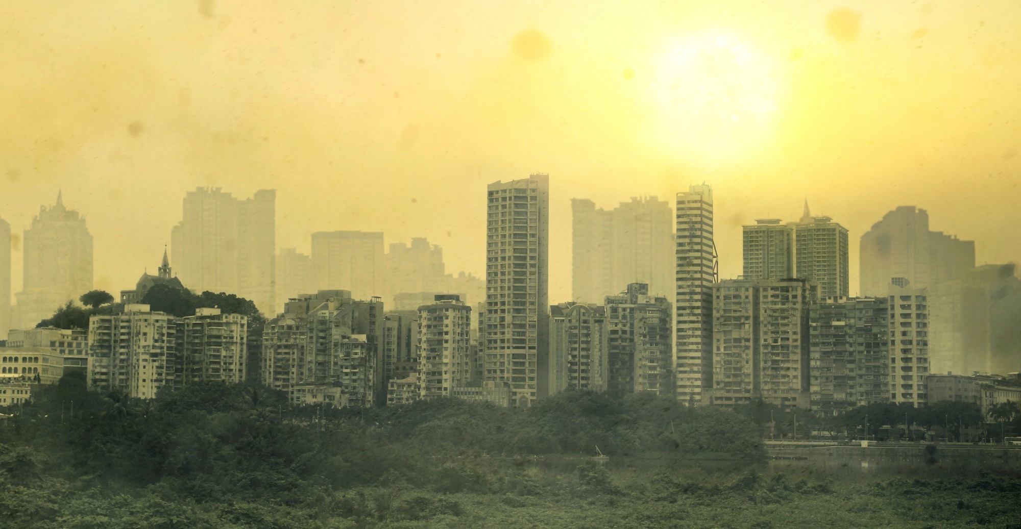 Urban skyline with multiple high-rise buildings, engulfed by a thing layer of smog